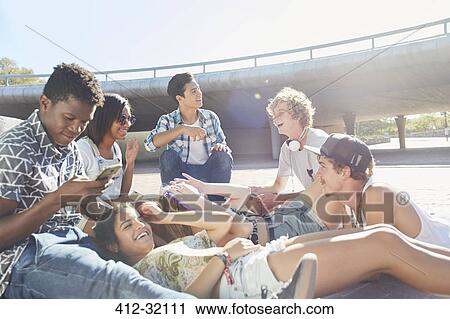 Teenage friends hanging out at sunny skate park View Large Photo Image Stock Image - Teenage friends hanging out at sunny skate park. Fotosearch