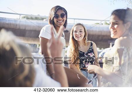 Stock Image - Teenage friends hanging out gesturing peace sign. Fotosearch
