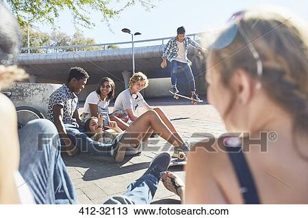 Teenage friends hanging out skateboarding at sunny skate park View Large Photo Image Stock Image - Teenage friends hanging out skateboarding at sunny skate park. Fotosearch
