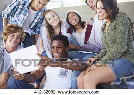 Stock Image - Teenage friends hanging out taking selfie with digital tablet. Fotosearch