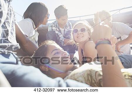 Teenage friends hanging out texting on sunny day View Large Photo Image Stock Photo - Teenage friends hanging out texting on sunny day. Fotosearch