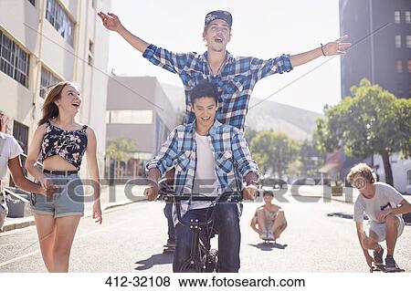 Teenage friends riding BMX bicycle and skateboarding on sunny urban street View Large Photo Image Stock Photo - Teenage friends riding BMX bicycle and skateboarding on sunny urban street. Fotosearch
