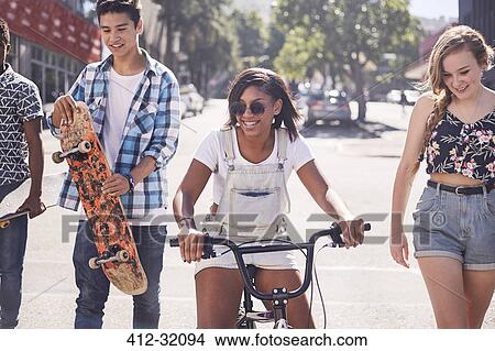 Picture - Teenage friends with skateboard and BMX bicycle on sunny urban street. Fotosearch