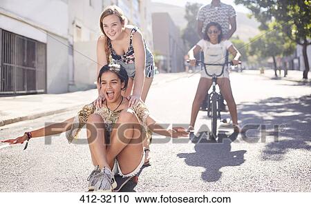 Teenage girls riding skateboard and BMX bicycle on sunny urban street View Large Photo Image Stock Image - Teenage girls riding skateboard and BMX bicycle on sunny urban street. Fotosearch