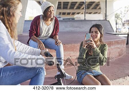 Teenage girls using camera phone at skate park View Large Photo Image Stock Photo - Teenage girls using camera phone at skate park. Fotosearch