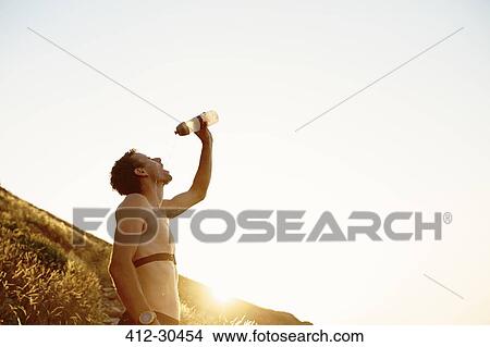 Picture - Tired male runner pouring water on face. Fotosearch