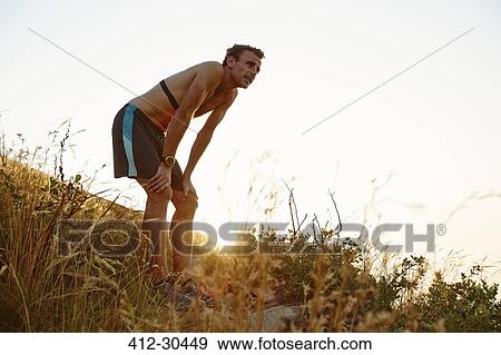 Tired male runner with hands on knees on grassy trail View Large Photo Image Stock Photo - Tired male runner with hands on knees on grassy trail. Fotosearch