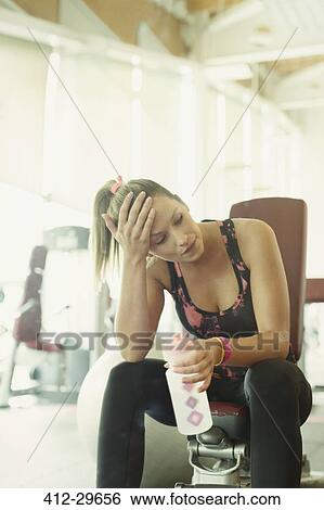 Tired woman resting and drinking water at gym View Large Photo Image Stock Photograph - Tired woman resting and drinking water at gym. Fotosearch