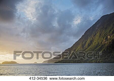 Stock Photograph - Tranquil ocean and cliff, Doubtful Sound, South Island New Zealand. Fotosearch