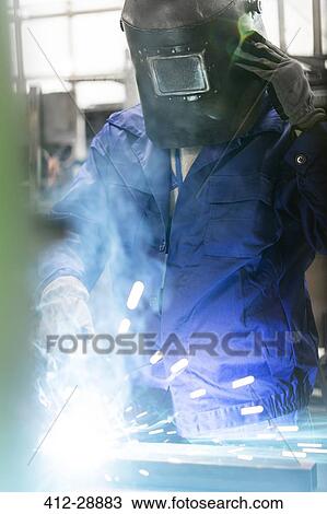 Welder in protective workwear working in factory View Large Photo Image Stock Image - Welder in protective workwear working in factory. Fotosearch