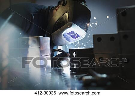 Stock Photograph - Welder using welding torch on steel in steel factory. Fotosearch