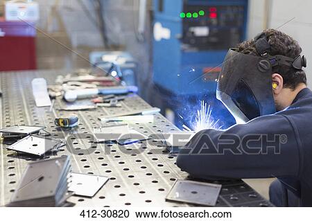Stock Image - Welder welding pieces in steel factory. Fotosearch