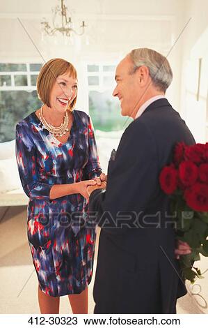 Well-dressed husband surprising wife with rose bouquet View Large Photo Image Stock Image - Well-dressed husband surprising wife with rose bouquet. Fotosearch