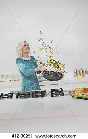 Woman cooking flipping vegetables in skillet in kitchen View Large Photo Image Stock Image - Woman cooking flipping vegetables in skillet in kitchen. Fotosearch