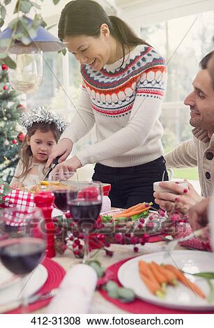Stock Photo - Woman cutting turkey at Christmas table. Fotosearch