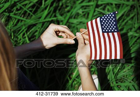 Stock Photo - Woman holding American flag in sunny grass. Fotosearch