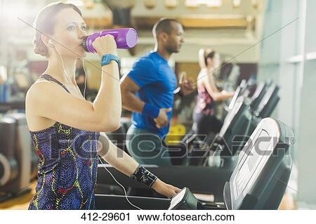 Stock Image - Woman on treadmill drinking water. Fotosearch