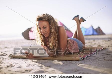 Woman reading digital tablet on beach mat View Large Photo Image Picture - Woman reading digital tablet on beach mat. Fotosearch