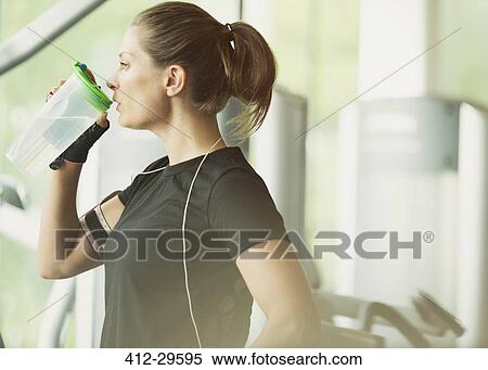 Woman resting and drinking water at gym View Large Photo Image Stock Photography - Woman resting and drinking water at gym. Fotosearch