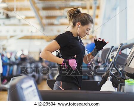 Woman running on treadmill at gym with headphones View Large Photo Image Picture - Woman running on treadmill at gym with headphones. Fotosearch