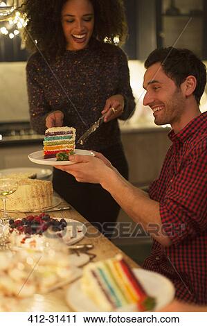 Stock Image - Woman serving layer cake to man at table. Fotosearch