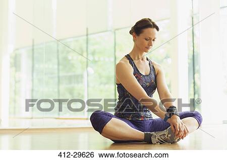 Stock Photograph - Woman stretching in cobblers pose in gym studio. Fotosearch