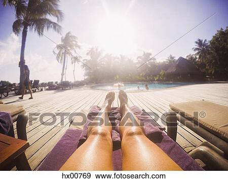 Woman sunbathing at sunny tropical poolside View Large Photo Image Stock Photo - Woman sunbathing at sunny tropical poolside. Fotosearch