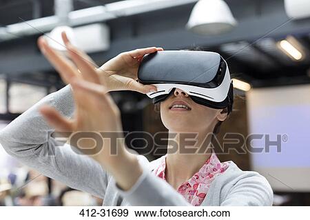 Stock Photo - Woman trying virtual reality simulator glasses glasses reaching. Fotosearch