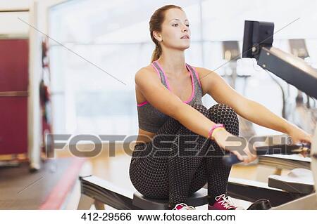 Woman using rowing machine at gym View Large Photo Image Stock Photograph - Woman using rowing machine at gym. Fotosearch