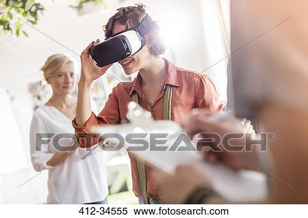 Stock Photography - Woman using virtual reality simulator glasses in office. Fotosearch