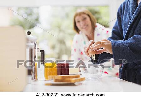 Woman watching husband crack egg in kitchen View Large Photo Image Stock Photo - Woman watching husband crack egg in kitchen. Fotosearch