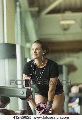 Stock Photography - Woman with headphones stretching leg at gym. Fotosearch