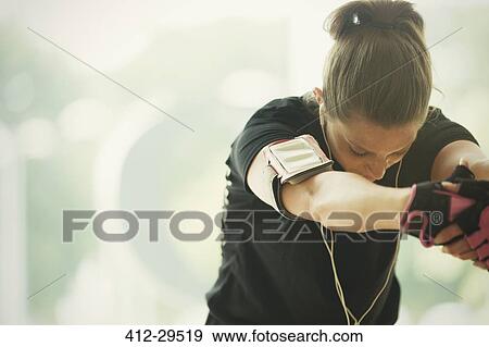 Stock Photo - Woman with mp3 player armband stretching arms. Fotosearch