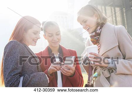Women texting and drinking coffee outdoors View Large Photo Image Stock Photo - Women texting and drinking coffee outdoors. Fotosearch