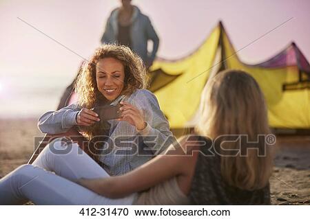 Women using camera phone on beach View Large Photo Image Stock Image - Women using camera phone on beach. Fotosearch