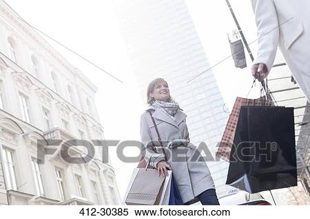 Women with shopping bags crossing city street below highrise View Large Photo Image Stock Photography - Women with shopping bags crossing city street below highrise. Fotosearch
