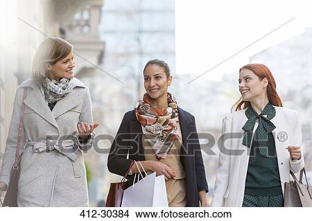 Picture - Women with shopping bags talking and walking in city. Fotosearch