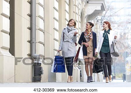 Women with shopping bags talking and walking on city sidewalk View Large Photo Image Stock Photo - Women with shopping bags talking and walking on city sidewalk. Fotosearch