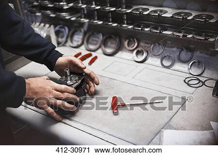 Stock Image - Worker assembling part in steel factory. Fotosearch
