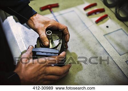 Stock Photo - Worker assembling parts in steel factory. Fotosearch