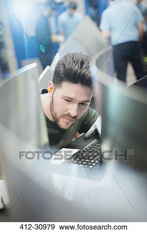 Stock Photo - Worker at computer keyboard in steel factory. Fotosearch