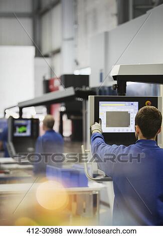 Stock Photo - Worker at control panel in steel factory. Fotosearch