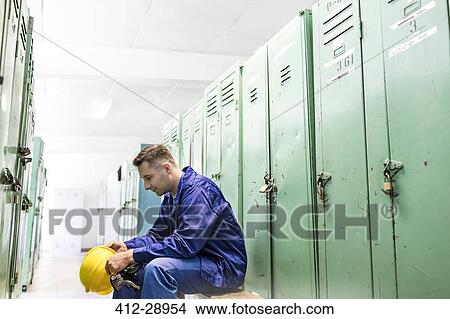 Worker holding hard-hat in locker room View Large Photo Image Picture - Worker holding hard-hat in locker room. Fotosearch
