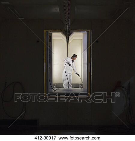 Stock Photo - Worker in clean suit in steel factory. Fotosearch