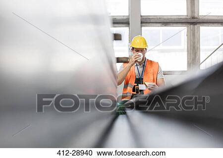 Worker in protective workwear drinking coffee in factory View Large Photo Image Stock Image - Worker in protective workwear drinking coffee in factory. Fotosearch