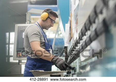 Stock Image - Worker in protective workwear working in factory. Fotosearch
