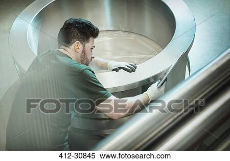 Stock Photography - Worker inspecting part in steel factory. Fotosearch