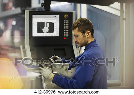 Stock Photograph - Worker inspecting steel at control panel in steel factory. Fotosearch