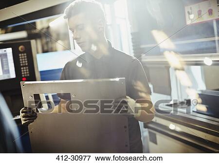 Stock Photo - Worker lifting steel part in steel factory. Fotosearch