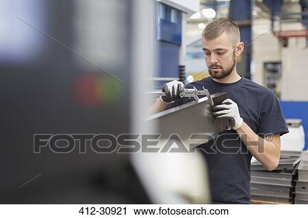 Stock Image - Worker measuring steel with calipers in steel factory. Fotosearch